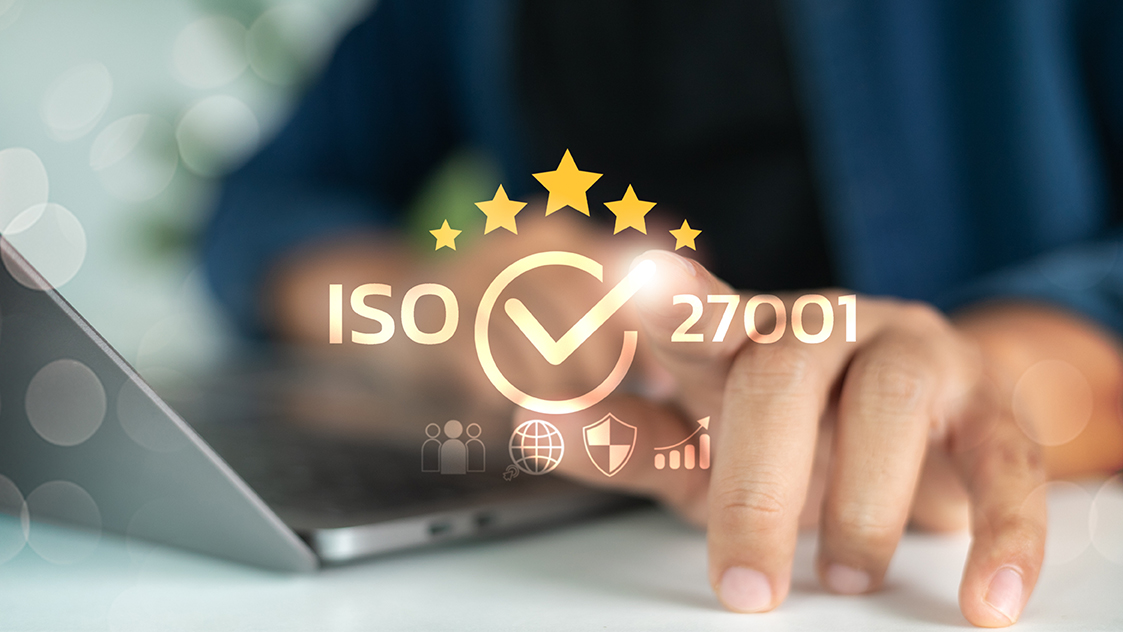 Ein abstrahiertes Zeichen für die ISO-Auszeichnung vor Händen an einem Laptop