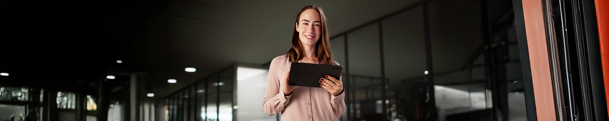 Eine Bankangestellte lächelt zufrieden während sie an ihrem Tablett arbeitet