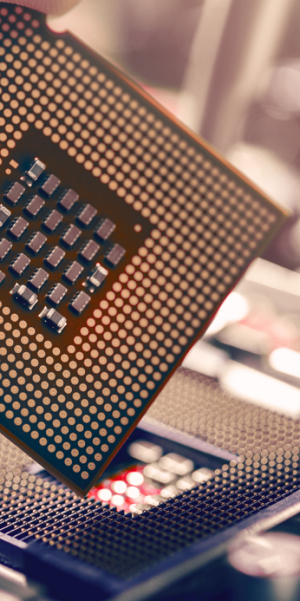 Hand hält einen Prozessor über dem Sockel eines Computer-Mainboards zur Installation.