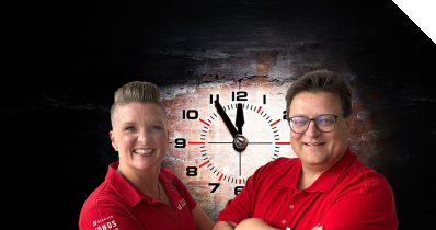 Die Datenbankexperten Andreas Ströbel und Frauke Jerabeck vor einer Uhr, die fünf vor zwölf anzeigt