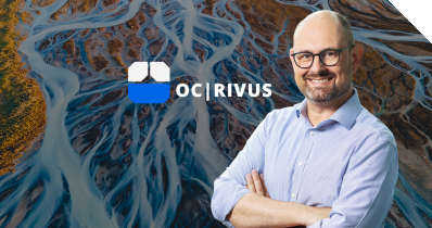 OPITZ CONSULTING Geschäftsführer Tom Gansor vor dem Logo von OC|RIVUS