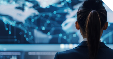 Frau sitzt in einem Kontrollraum vor diversen Bildschirmen, auf denen eine Weltkarte und diverse Daten angezeigt werden. 