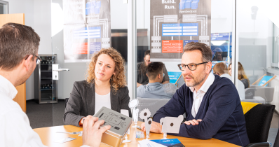 Kollegen besprechen sich an einem Bürotisch.