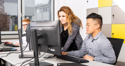 Eine IT-Expertin und zwei IT-Experten bei der Teamarbeit im Office